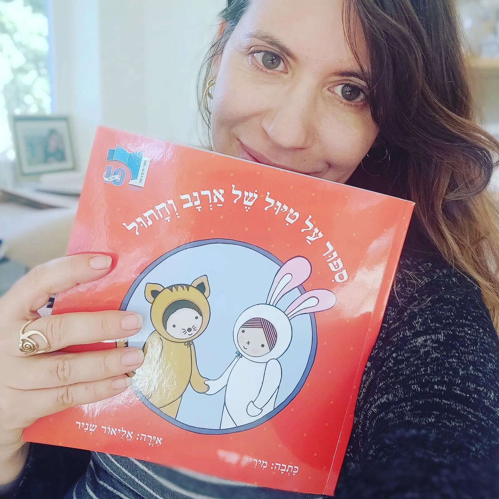אליאור שניר מחזיקה ספר ילדים שאיירה